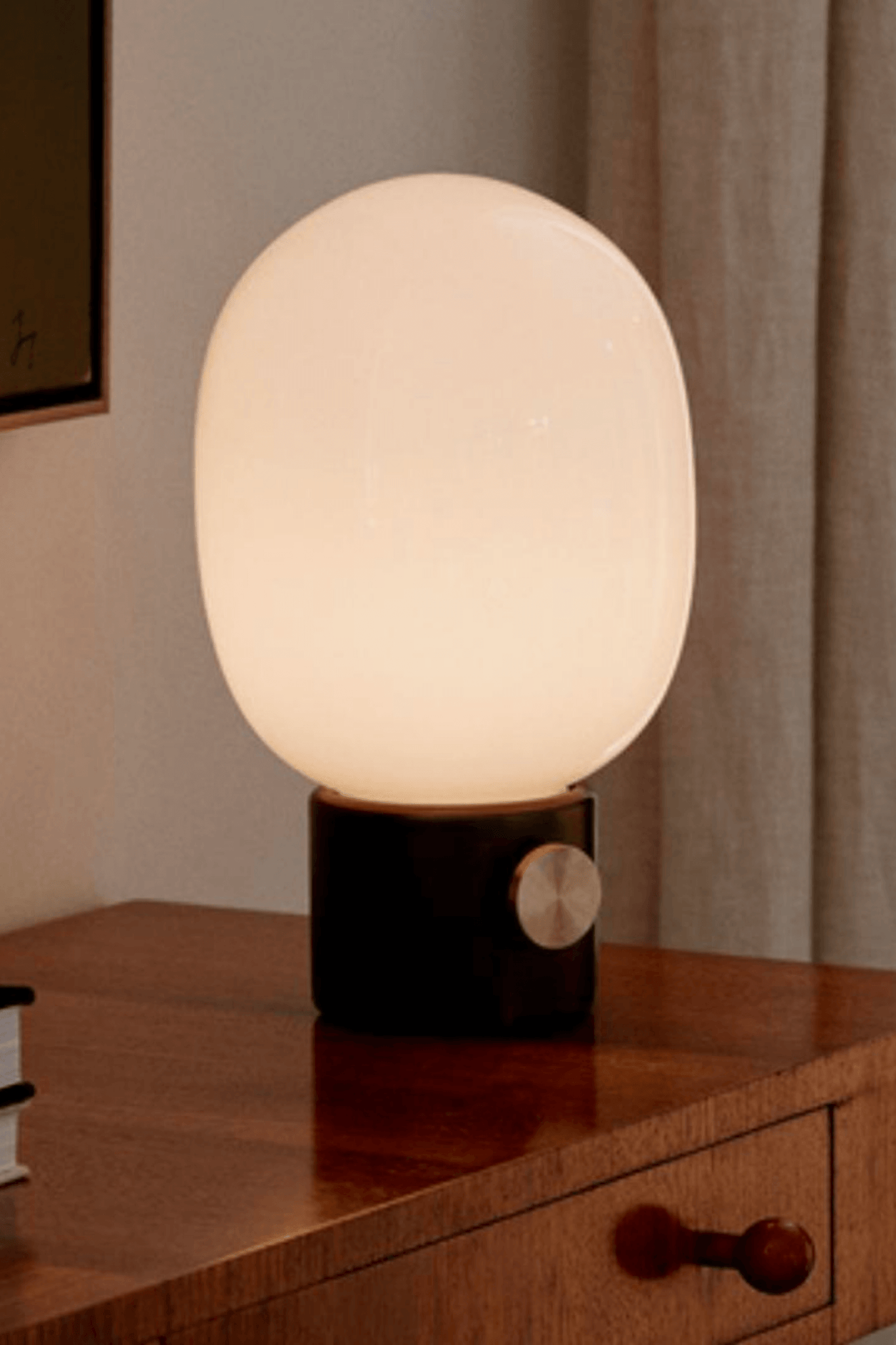 Black Portable JWDA Table Lamp by Menu, shown lit on an angle