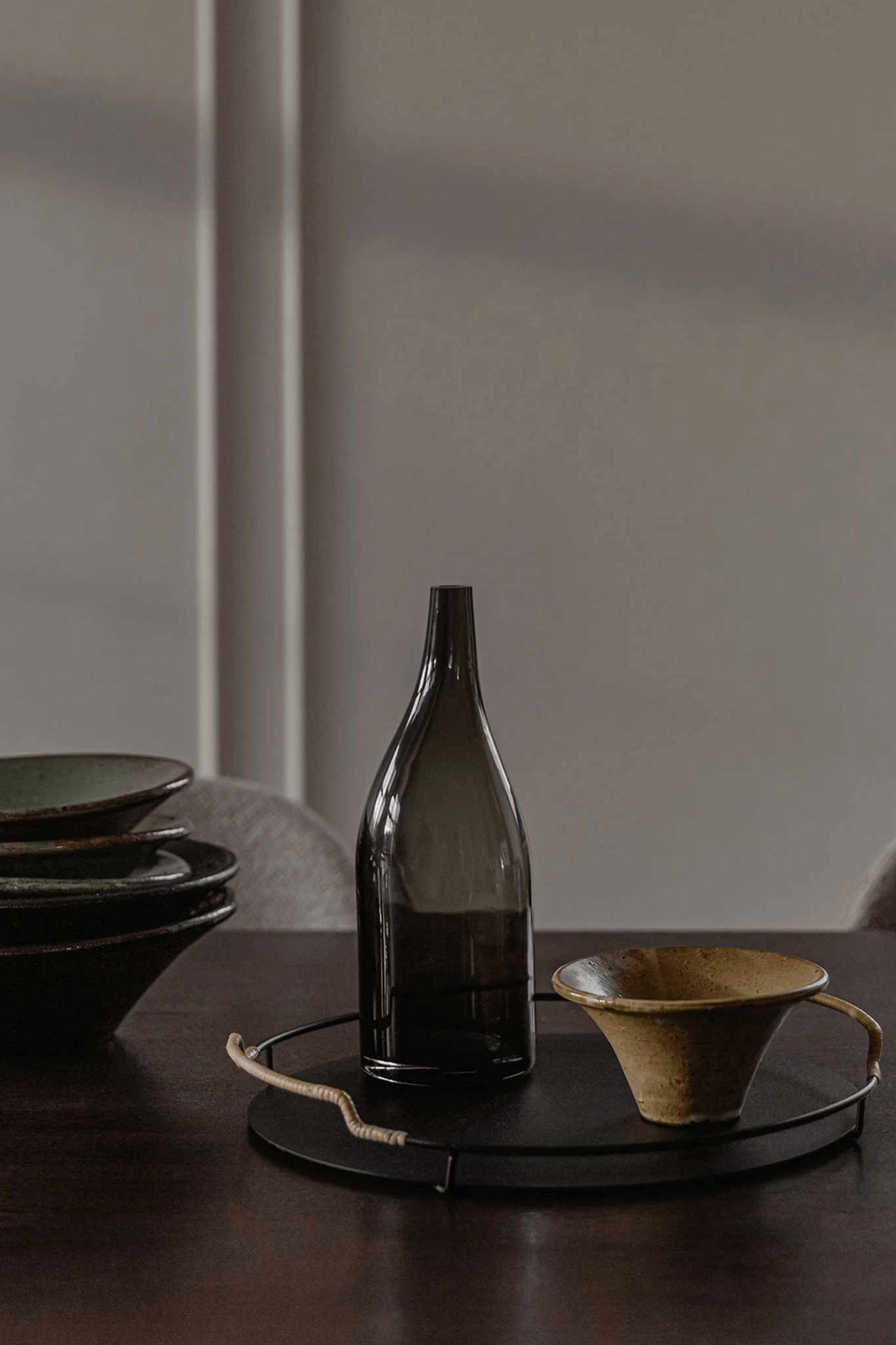 Black Balcony Serving Tray by Menu, shown on table with bottle and vessel
