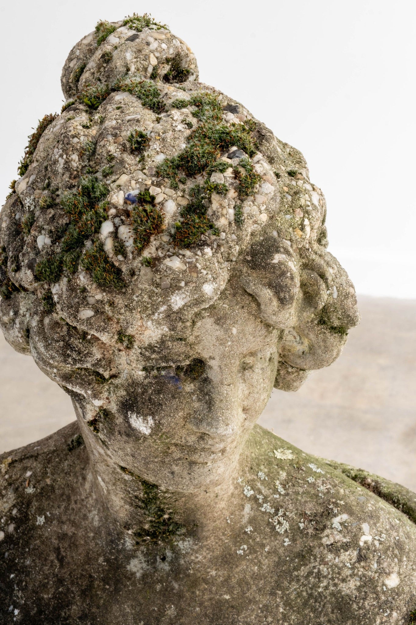 Vintage Stone statue with mossy hair against a neutral background