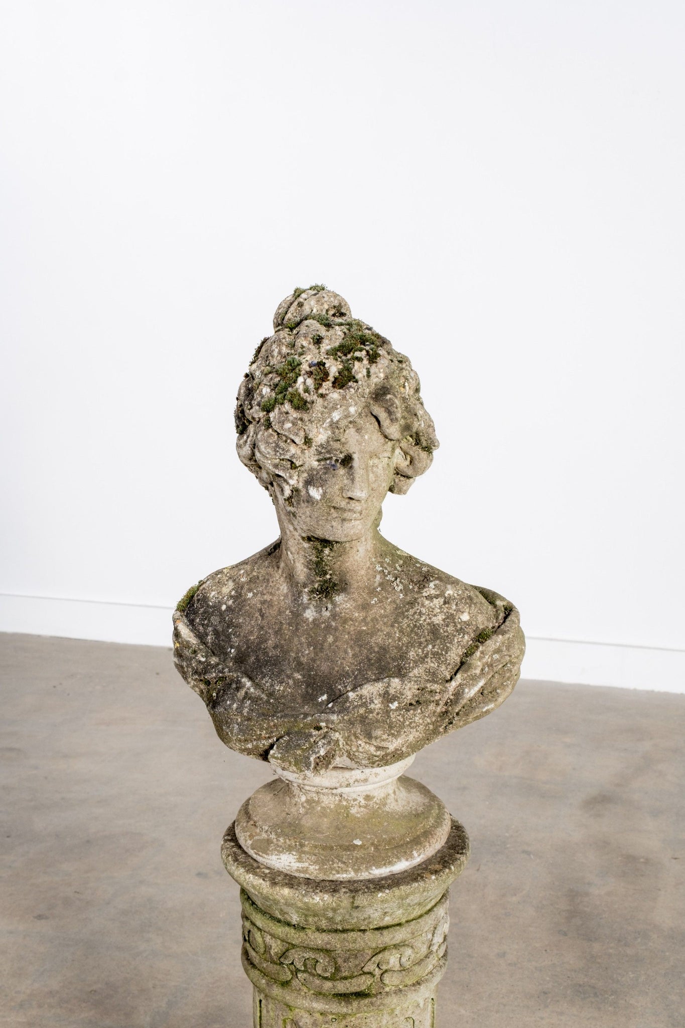 Vintage stone bust on a pedestal against a white background