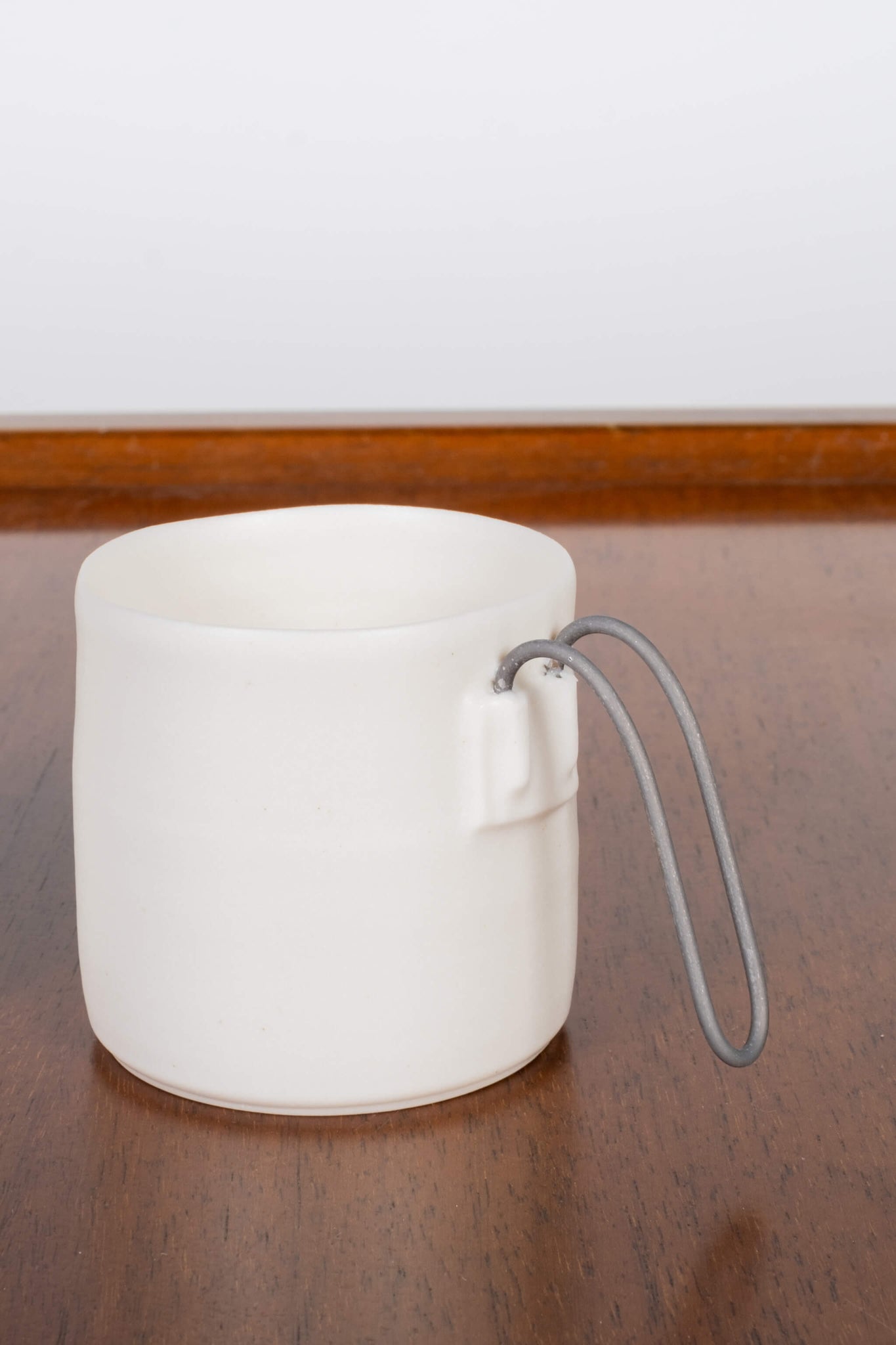 Porcelain Espresso cup with straight metal handle, front view, handle detail