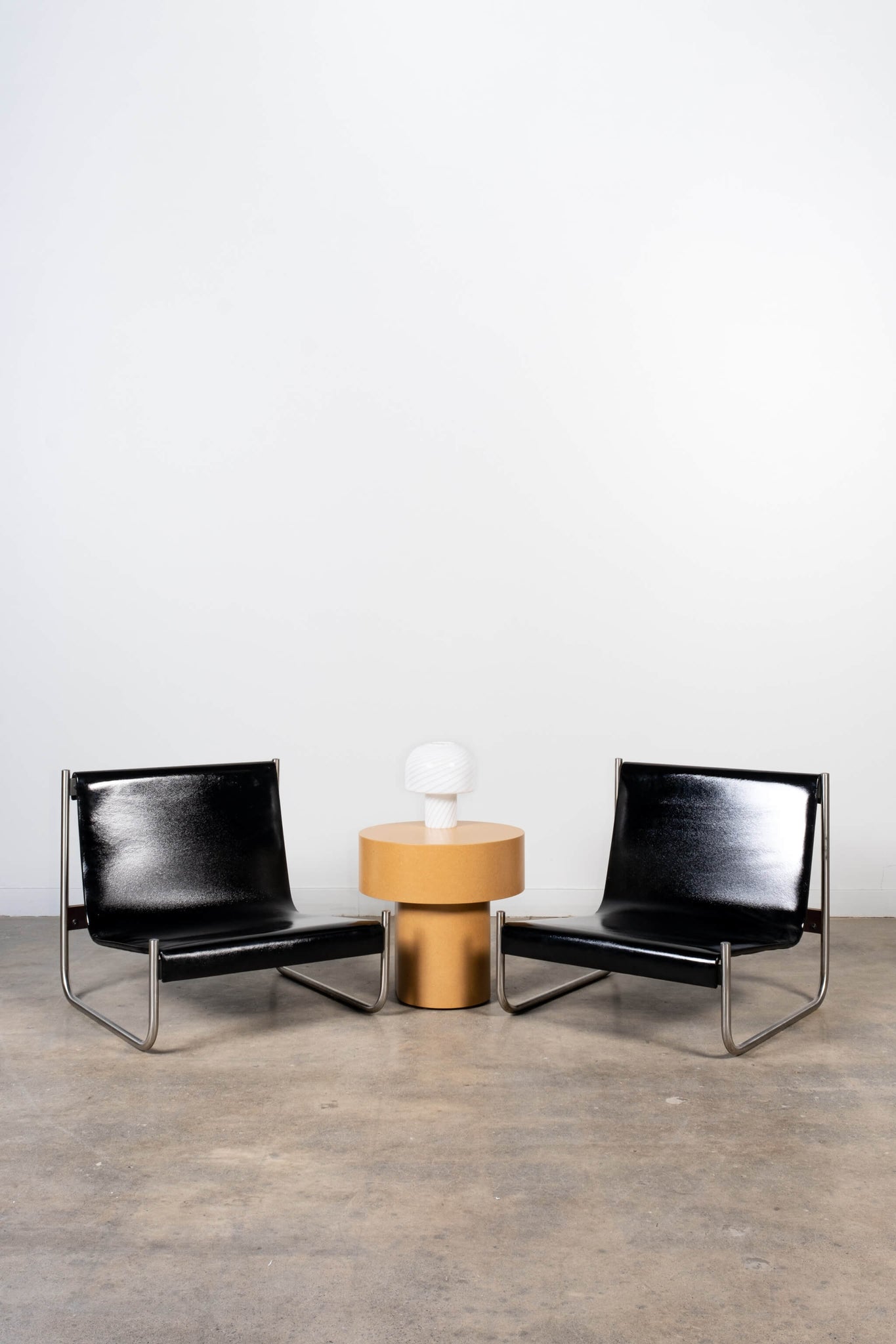 Pair of Vintage Black Patent Leather Chrome Sling Chairs Scuola Di Torino, shown side by side with side table and lamp